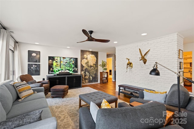 living room with ceiling fan, brick wall, and light wood-type flooring