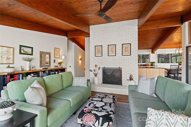 living room featuring a fireplace, lofted ceiling with beams, wood-type flooring, ceiling fan with notable chandelier, and wooden ceiling