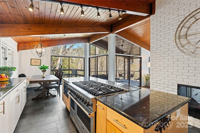 kitchen featuring wood ceiling, a kitchen island, a notable chandelier, dark stone counters, and range with two ovens