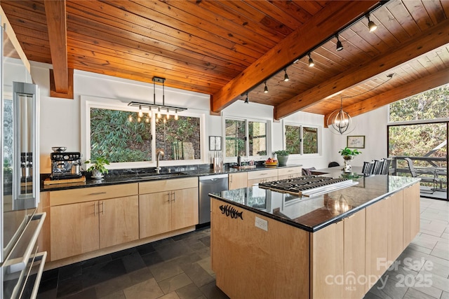 kitchen featuring appliances with stainless steel finishes, decorative light fixtures, a chandelier, a center island, and light brown cabinets