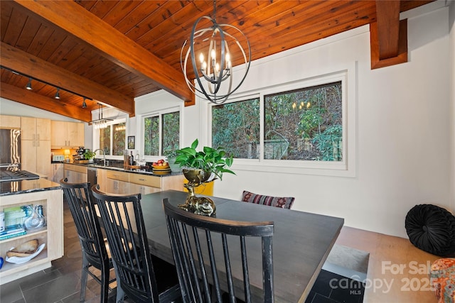 dining space featuring sink, wood ceiling, a notable chandelier, track lighting, and lofted ceiling with beams