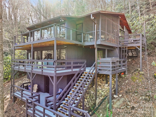 rear view of property featuring a sunroom and a deck