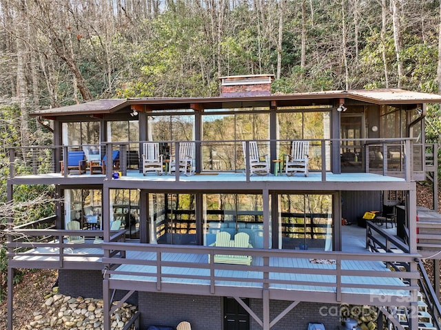 rear view of house with a wooden deck and a sunroom