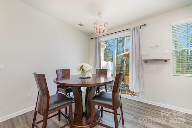 dining space with wood-type flooring and a notable chandelier