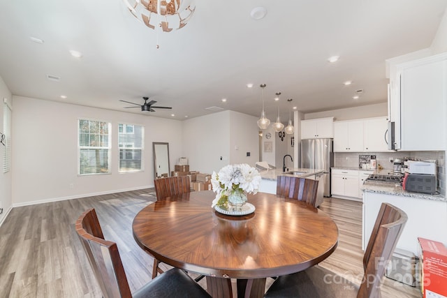 dining area with ceiling fan, sink, and light wood-type flooring