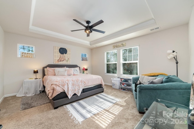 bedroom with light colored carpet, ceiling fan, and a tray ceiling