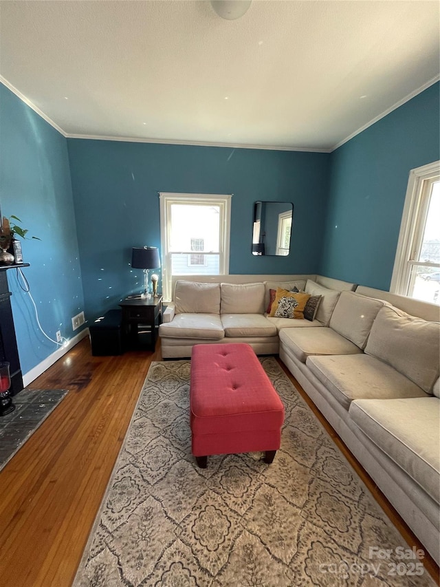 living area with a healthy amount of sunlight, crown molding, baseboards, and wood finished floors