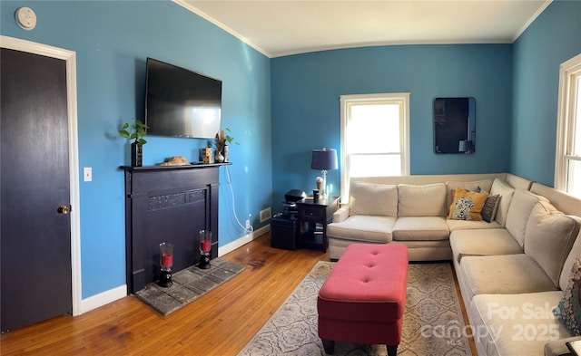 living room featuring baseboards, a fireplace, ornamental molding, and wood finished floors