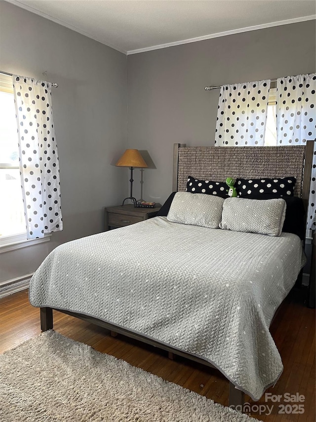 bedroom with wood finished floors and crown molding