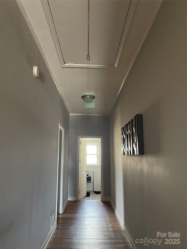 hallway featuring attic access, baseboards, visible vents, ornamental molding, and wood finished floors