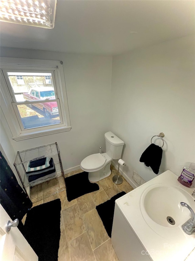 bathroom with a sink, toilet, and baseboards