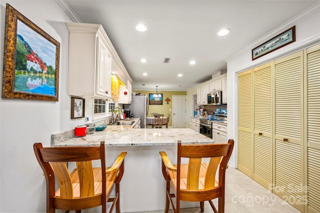 kitchen featuring appliances with stainless steel finishes, decorative light fixtures, white cabinetry, sink, and kitchen peninsula