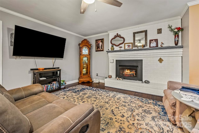 living room featuring a brick fireplace, crown molding, wood-type flooring, and ceiling fan