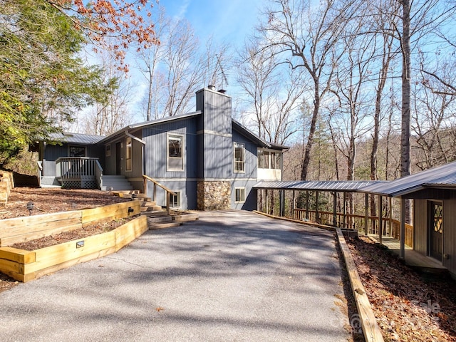 view of side of property featuring metal roof, driveway, and a chimney