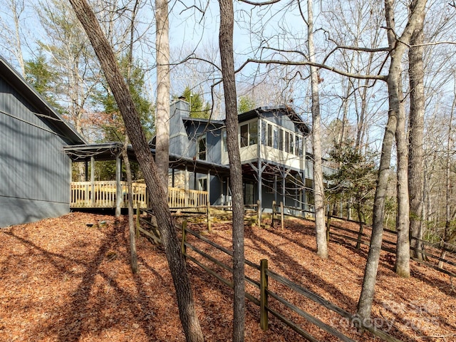 back of house with a deck, a sunroom, and a chimney