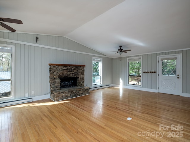 unfurnished living room featuring light wood finished floors, vaulted ceiling, a fireplace, and baseboard heating