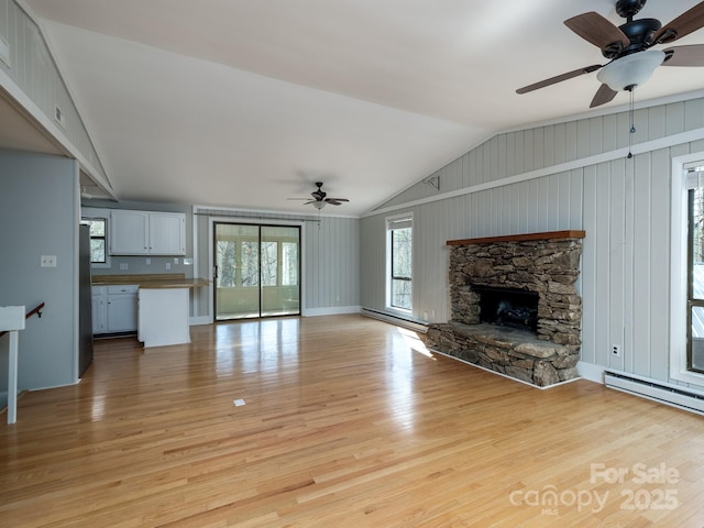 unfurnished living room featuring a fireplace, vaulted ceiling, light wood finished floors, and ceiling fan