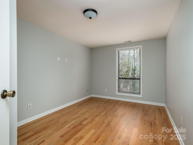 empty room featuring light wood-type flooring, visible vents, and baseboards