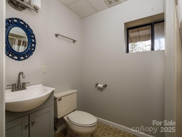 bathroom with visible vents, toilet, vanity, baseboards, and tile patterned floors