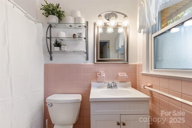 bathroom with vanity, tile walls, and toilet