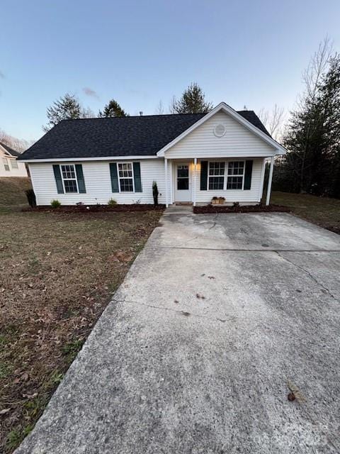 ranch-style house featuring driveway, roof with shingles, and a front yard