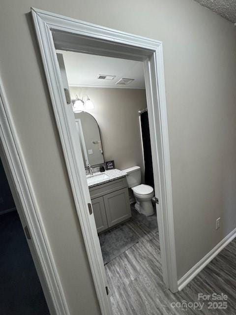 bathroom with vanity, wood finished floors, toilet, and baseboards