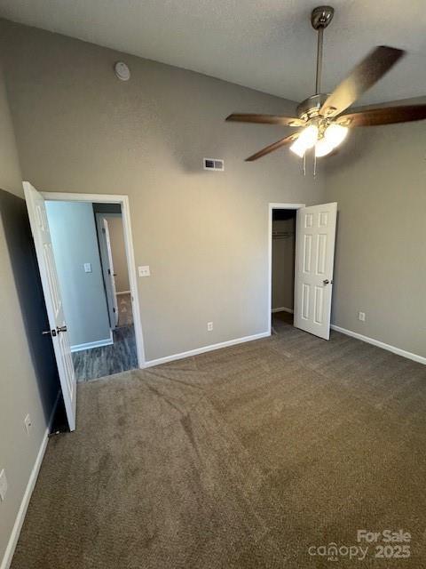 unfurnished bedroom with a closet, visible vents, dark carpet, and baseboards