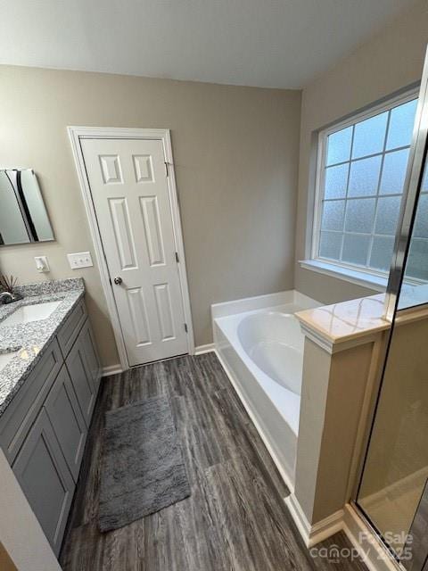 bathroom featuring wood finished floors, vanity, baseboards, a shower stall, and a bath