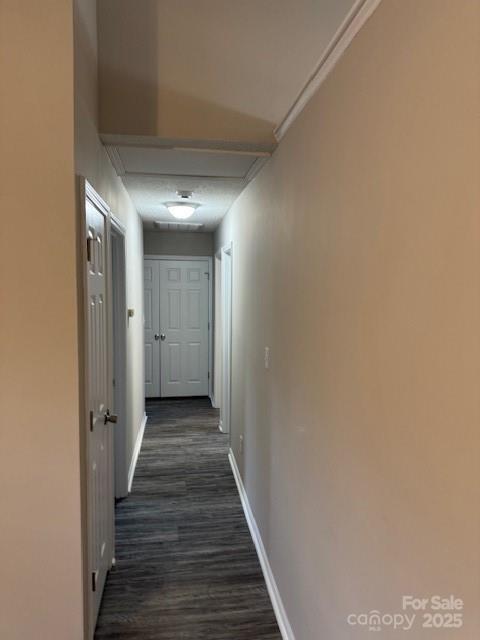 corridor with dark wood-type flooring and baseboards