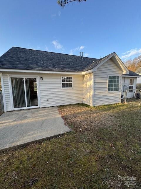 rear view of property with a patio, roof with shingles, and fence