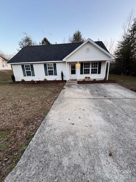 ranch-style house featuring a shingled roof, concrete driveway, and a front lawn