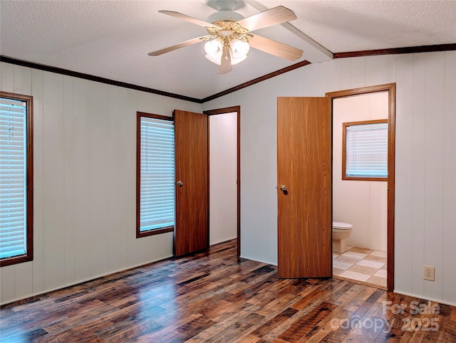 unfurnished bedroom featuring connected bathroom, dark wood-type flooring, a textured ceiling, and ornamental molding