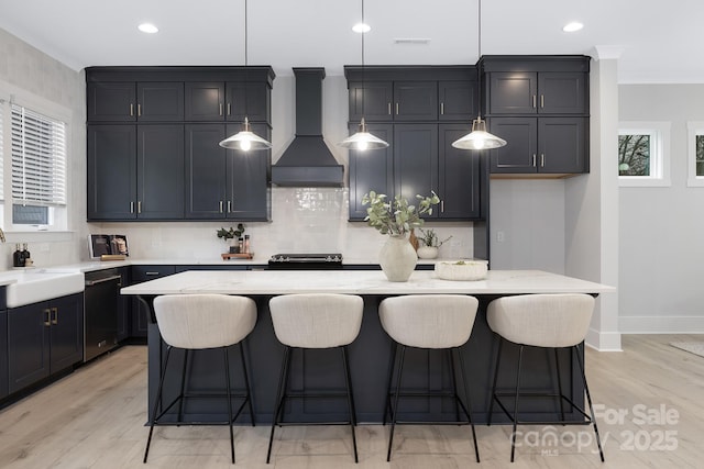 kitchen featuring dishwashing machine, hanging light fixtures, custom range hood, and a kitchen island