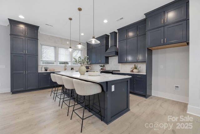 kitchen featuring pendant lighting, a breakfast bar, backsplash, a kitchen island, and custom exhaust hood