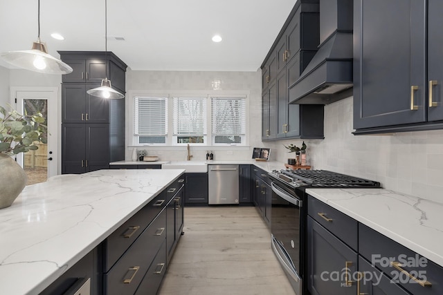 kitchen with pendant lighting, appliances with stainless steel finishes, premium range hood, light stone counters, and tasteful backsplash