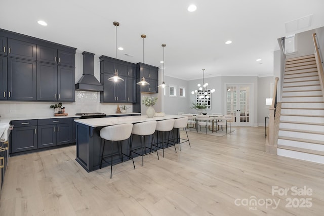 kitchen featuring a breakfast bar area, a center island, custom range hood, pendant lighting, and decorative backsplash