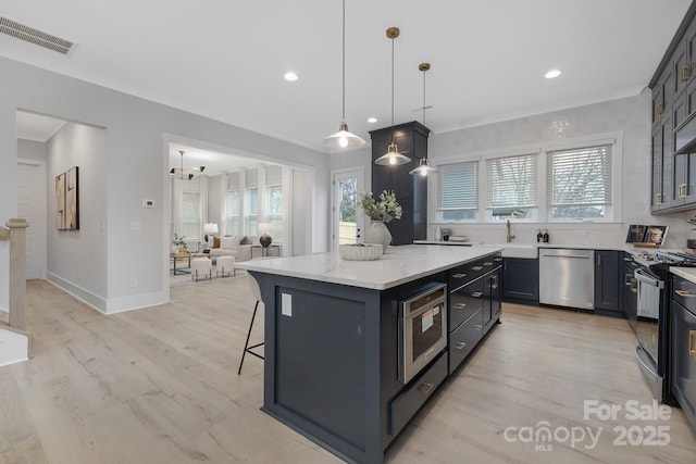 kitchen with a center island, hanging light fixtures, a kitchen breakfast bar, stainless steel appliances, and light stone countertops