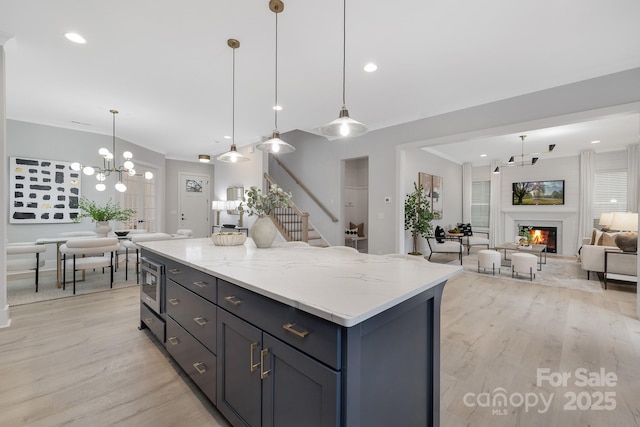 kitchen with crown molding, light stone countertops, light hardwood / wood-style floors, and decorative light fixtures