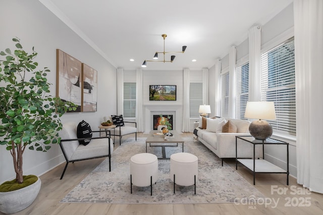 living room with ornamental molding, a chandelier, and light wood-type flooring