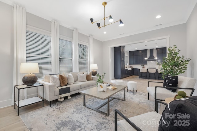 living room with crown molding, an inviting chandelier, and light hardwood / wood-style floors