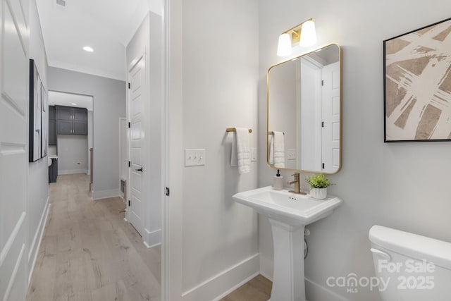 bathroom featuring ornamental molding, hardwood / wood-style floors, and toilet