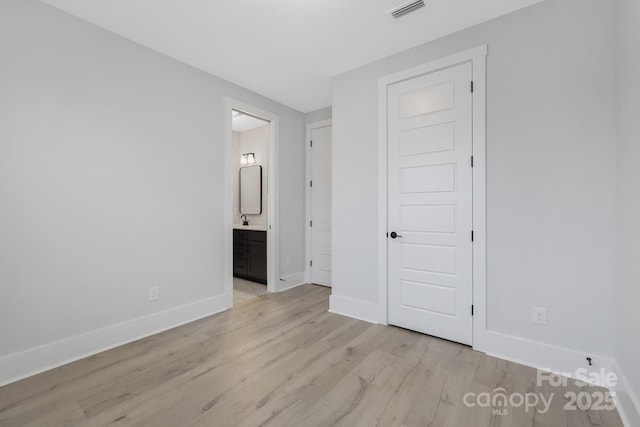 unfurnished bedroom featuring sink, connected bathroom, and light wood-type flooring