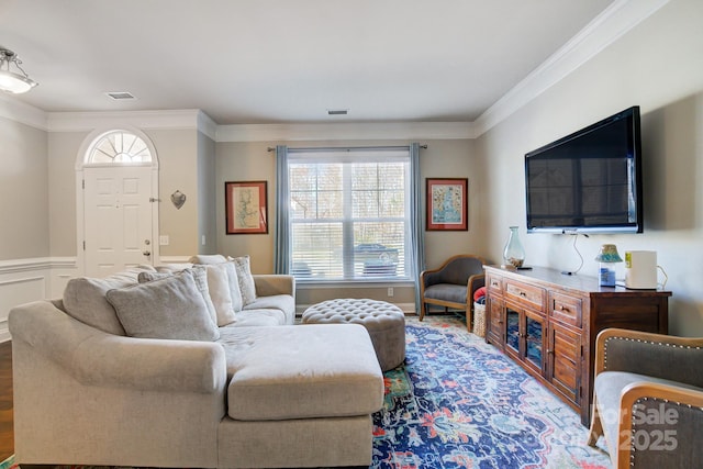 living room with ornamental molding, wainscoting, wood finished floors, and visible vents