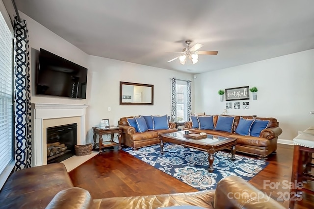 living room featuring a ceiling fan, a glass covered fireplace, and wood finished floors