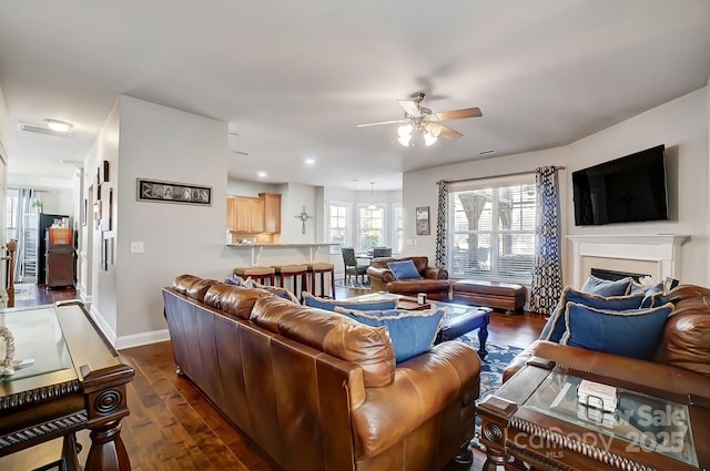 living room with dark wood-style floors, a fireplace, baseboards, and a ceiling fan