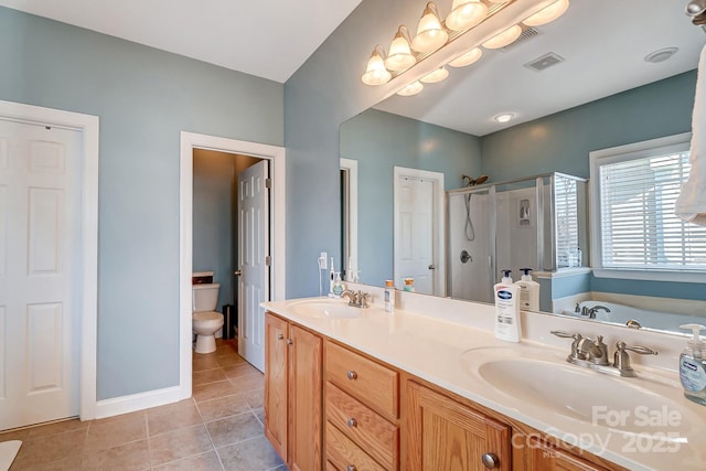 bathroom with double vanity, a sink, a shower stall, and tile patterned floors