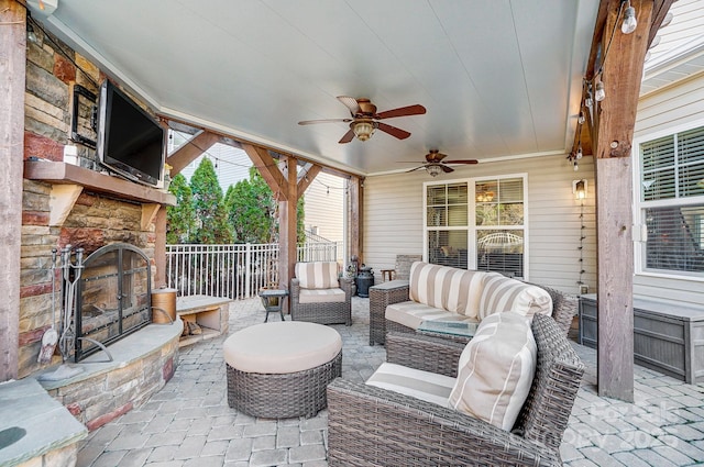 view of patio / terrace with ceiling fan, an outdoor living space with a fireplace, and fence