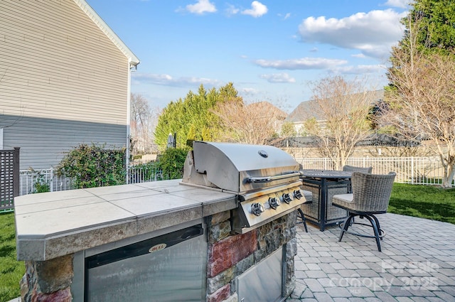 view of patio / terrace featuring an outdoor kitchen, fence, and a grill