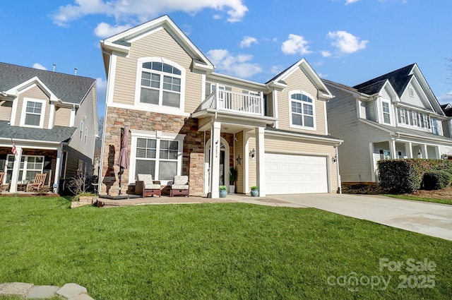 view of front of home featuring a front lawn, stone siding, a balcony, and concrete driveway