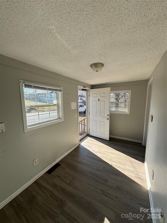 entrance foyer featuring a healthy amount of sunlight, visible vents, baseboards, and wood finished floors